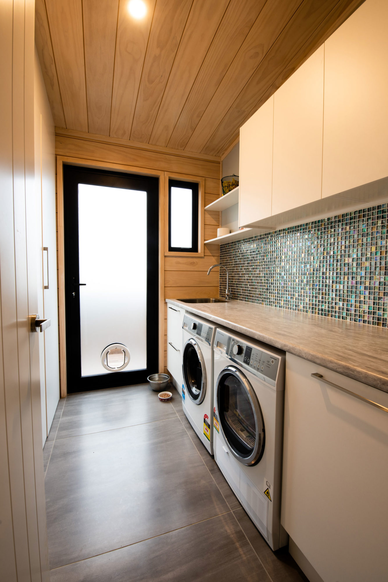 Lockwood home laundry with mosaic tiles and generous bench top